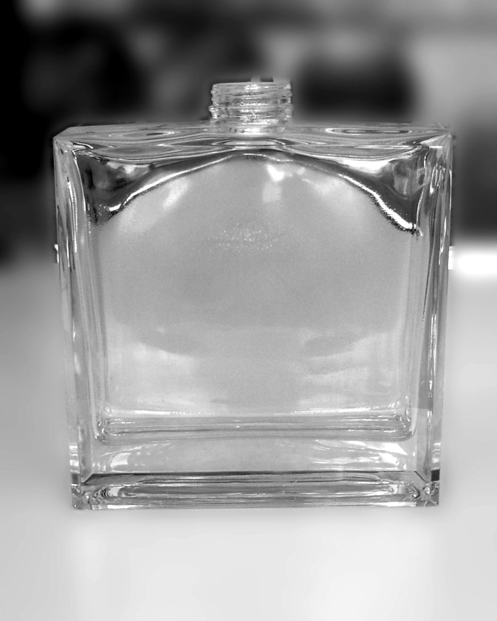 Verre du factice géant Bleu de Chanel, posé sur une table, en noir et blanc